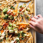 hand reaching for kimchi cheese fries