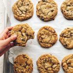 cookies on a sheet pan, with a hand holding one