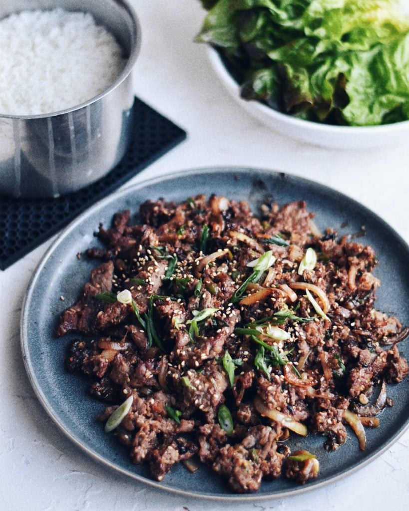 Korean beef bulgogi on a plate with rice and lettuce wraps on the side