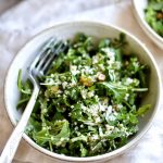 close up of arugula quinoa salad in bowl with fork