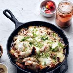 cheese buldak in cast iron skillet with scotch bonnet peppers and gochukaru in corner