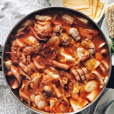 budae jjigae ingredients in electric hot pot on table