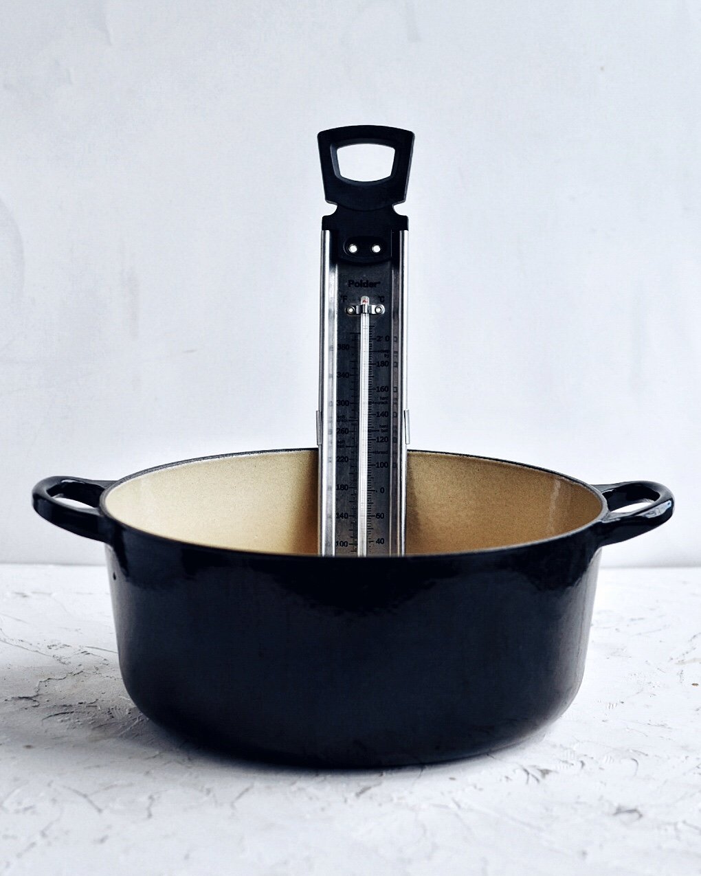 cast iron dutch oven with candy thermometer attached
