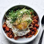 spam kimchi fried rice with fried egg and green onion garnish in bowl with spoon