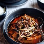 close up of yukgaejang in dark bowl with spoon