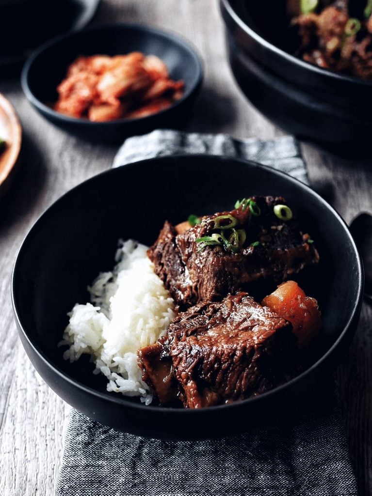 bowl of galbi jjim (Korean braised short ribs) with rice on grey napkin and wood table