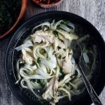 lemongrass chicken soup in black bowl with spoon