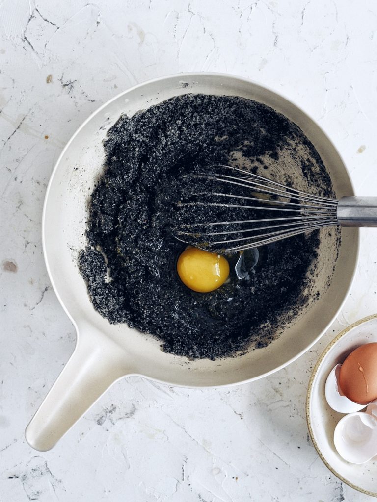 bowl with black sesame seeds and egg with whisk to the side