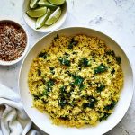 bowl of turmeric rice with lime wedges and coconut gremolata