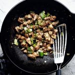 spicy chicken stir fry with leeks in wok with spatula on the side