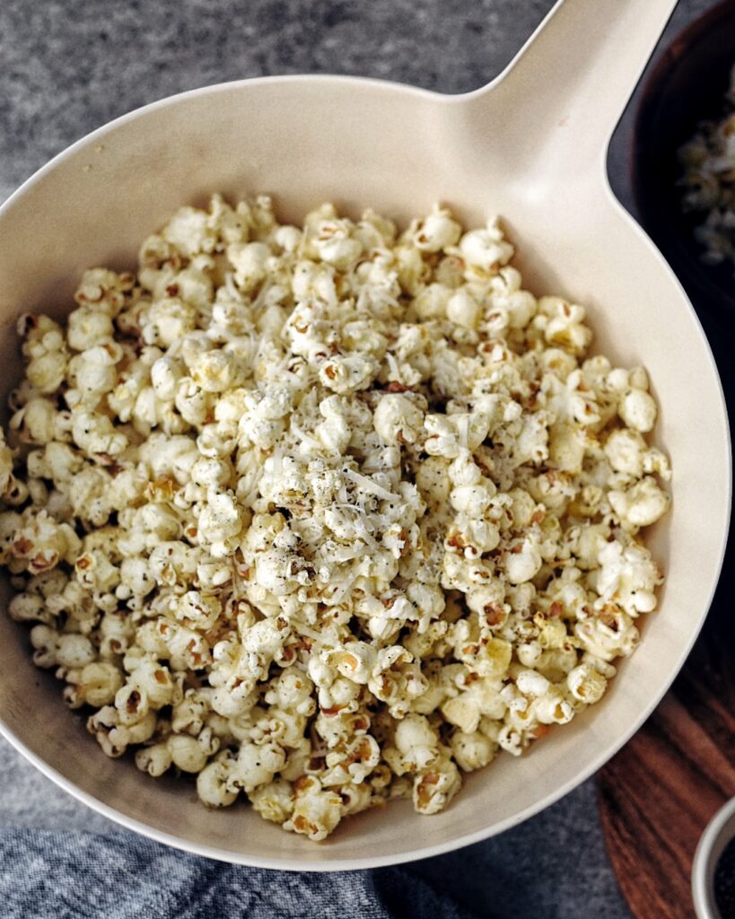 white bowl of parmesan popcorn with black pepper