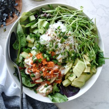 salmon poke bowl with salad base in white bowl
