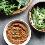 small bowl of ssamjang with green onions and lettuce wraps