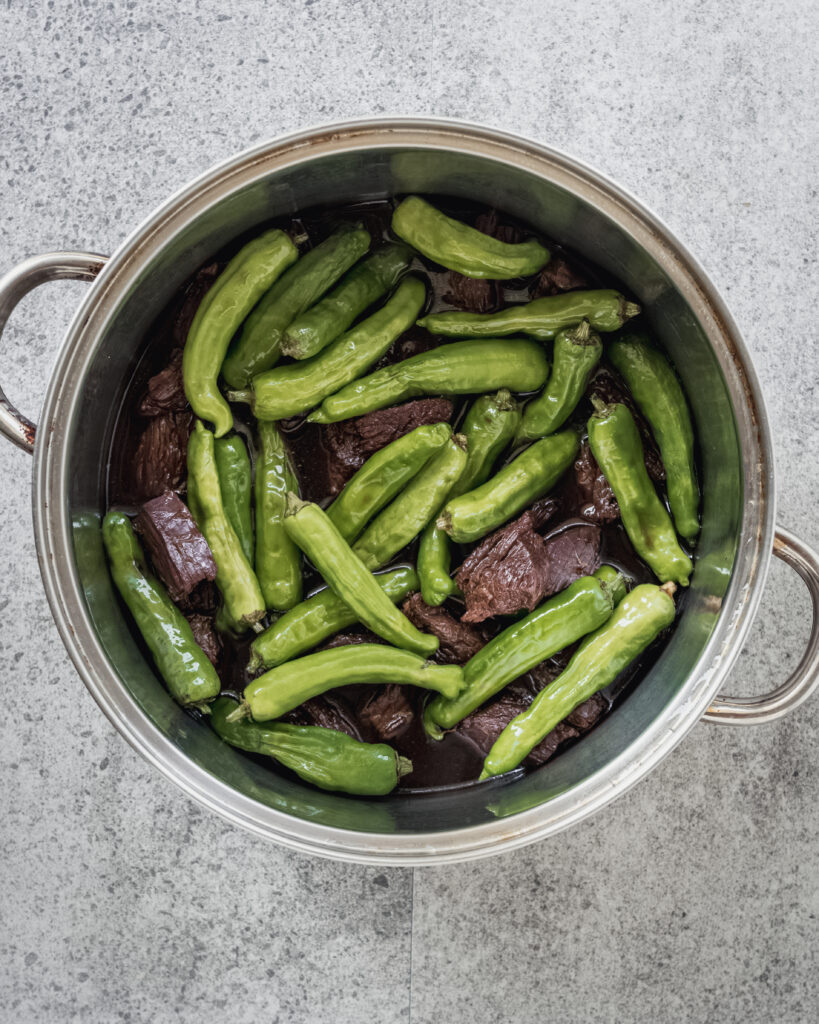 pot filled with shishito peppers and flank steak