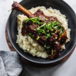shallow bowl filled with braised lamb shank on top of mashed potatoes
