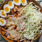 pan filled with cheesy tteokbokki with cabbage and hard boiled eggs