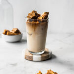 tall glass filled with Dalgona latte topped with honeycomb toffee