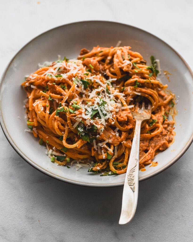 shallow bowl filled with creamy kimchi pasta with parmesan cheese and bacon