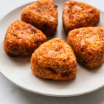 korean triangle rice balls with kimchi and cheese on a white plate