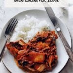 korean pork chops with kimchi pan sauce on plate with rice, fork, and knife