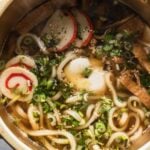 easy udon noodle soup with fish cakes and poached egg in gold cooking pot
