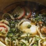 easy udon noodle soup with fish cakes and poached egg in gold cooking pot
