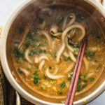 small pot filled with curry udon noodle soup