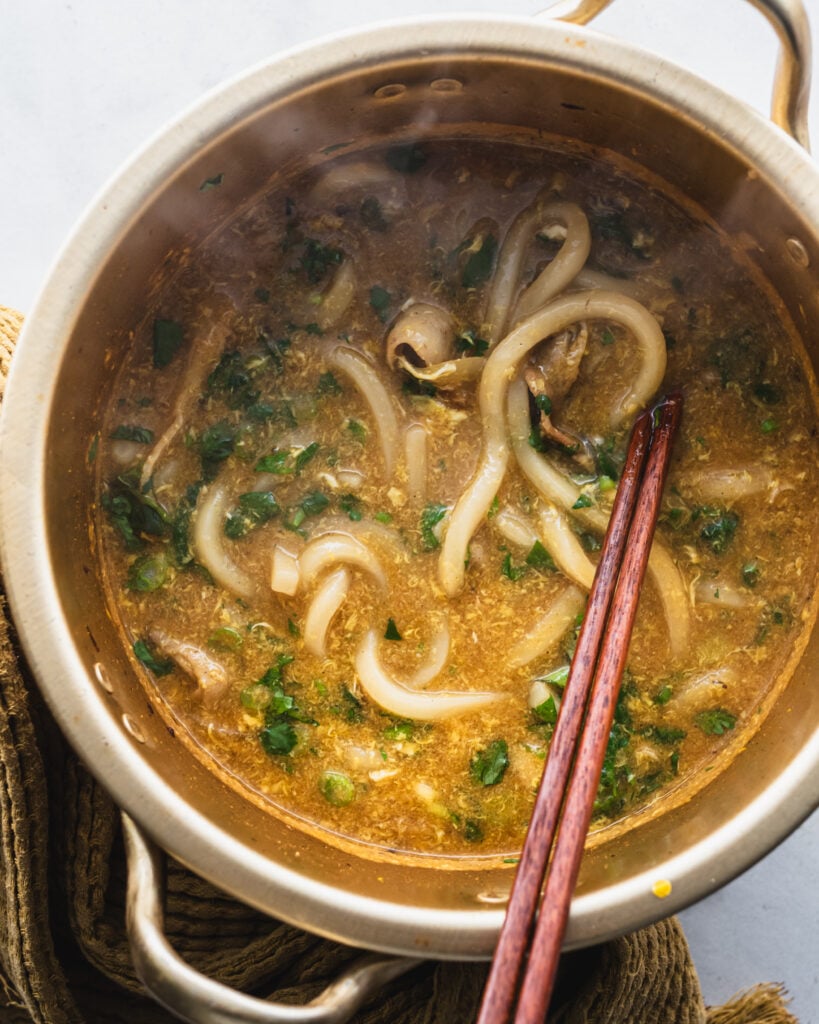 small pot filled with curry udon noodle soup