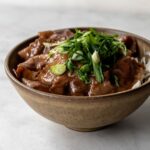 side view of pork donburi with green onions