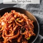 side view of spicy korean radish salad heaped into a bowl