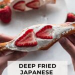 two hands holding a japanese fried cream sando with strawberries