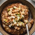 steel cut oatmeal with apple cinnamon in bowl with spoon on the side
