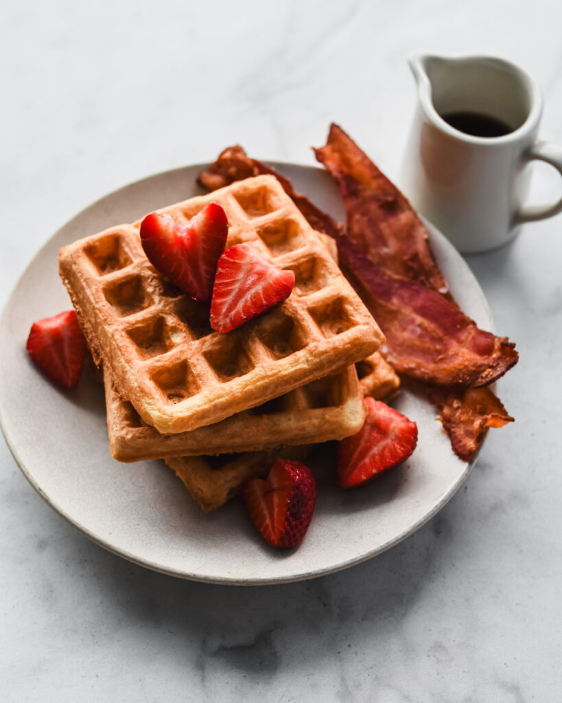 stacked mochi waffles in pile with strawberries and bacon