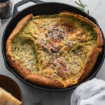savory dutch baby pancake with herbs and parmesan in cast iron skillet