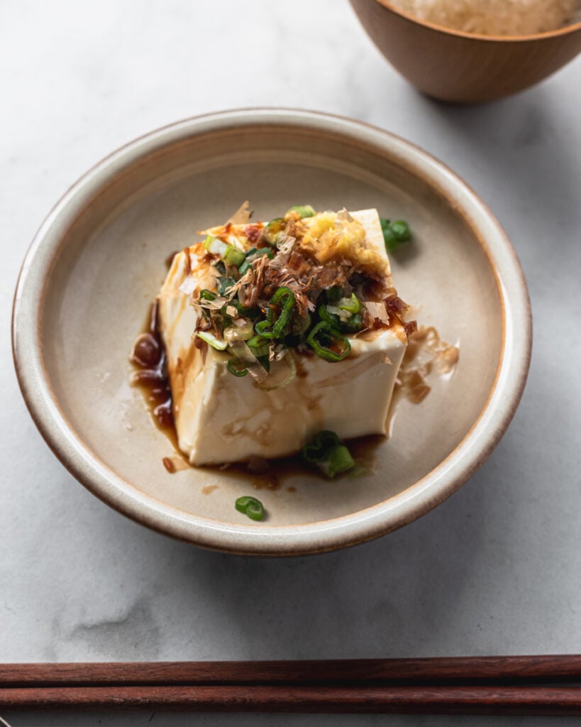 japanese cold tofu (hiyayakko) with soy sauce, green onion, ginger, and bonito flakes