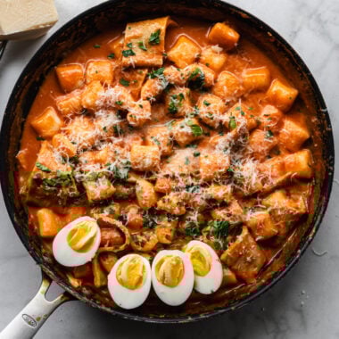 rose tteokbokki (korean rice cakes) in large skillet with halved hard boiled eggs