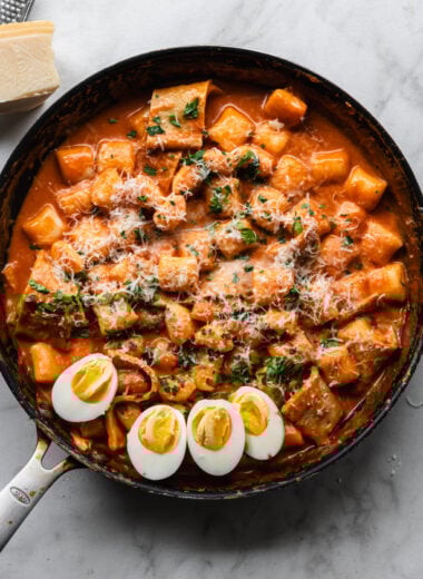 rose tteokbokki (korean rice cakes) in large skillet with halved hard boiled eggs