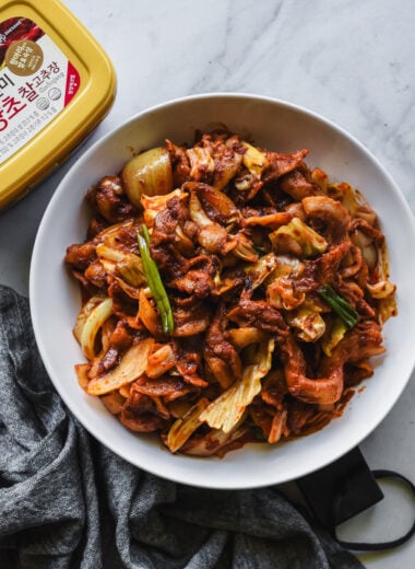 spicy korean pork on white serving platter with tub of gochujang nearby