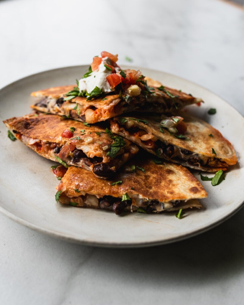 wedges of kimchi quesadilla stacked on top of each other on a plate