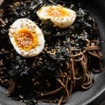 black bowl filled with korean perilla oil soba noodles and soft boiled egg