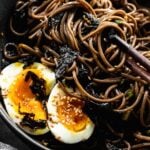 chopsticks reaching inside bowl of korean perilla oil noodles