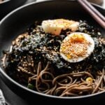 black bowl filled with korean perilla oil soba noodles and soft boiled egg