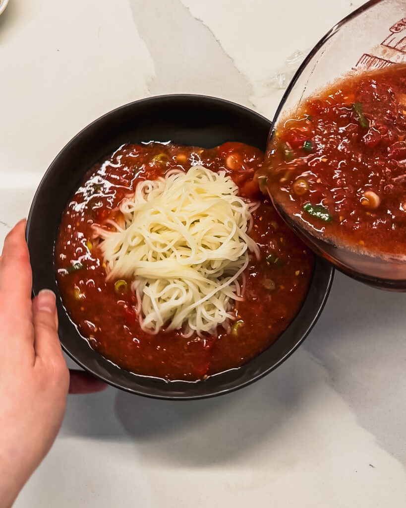 pouring tomato broth into bowl of tomato somyeon noodles