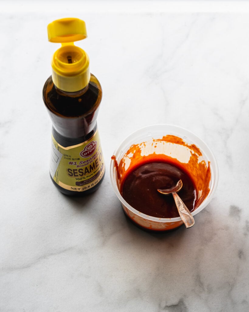 bottle of sesame oil and container filled with gochujang sauce