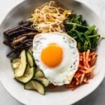 bibimbap korean rice bowl with ingredients in separate sections and fried egg on top
